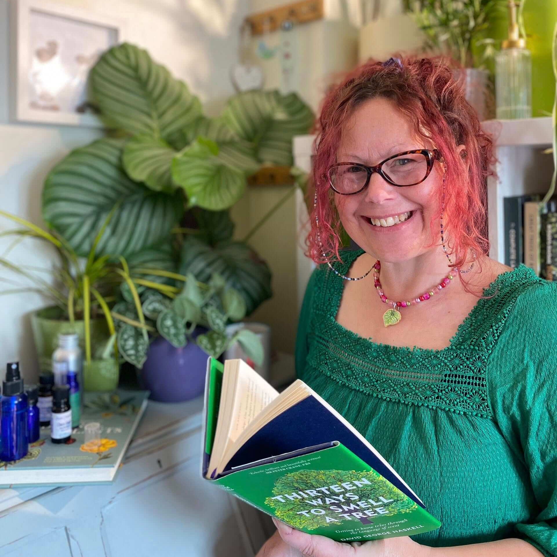 Woman holding a book titled '14 Ways to Self-Care' in a home setting with plants and bottles.