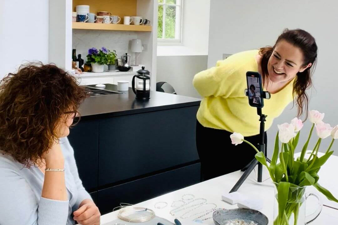 Two women in a kitchen setting, one looking at a smartphone.